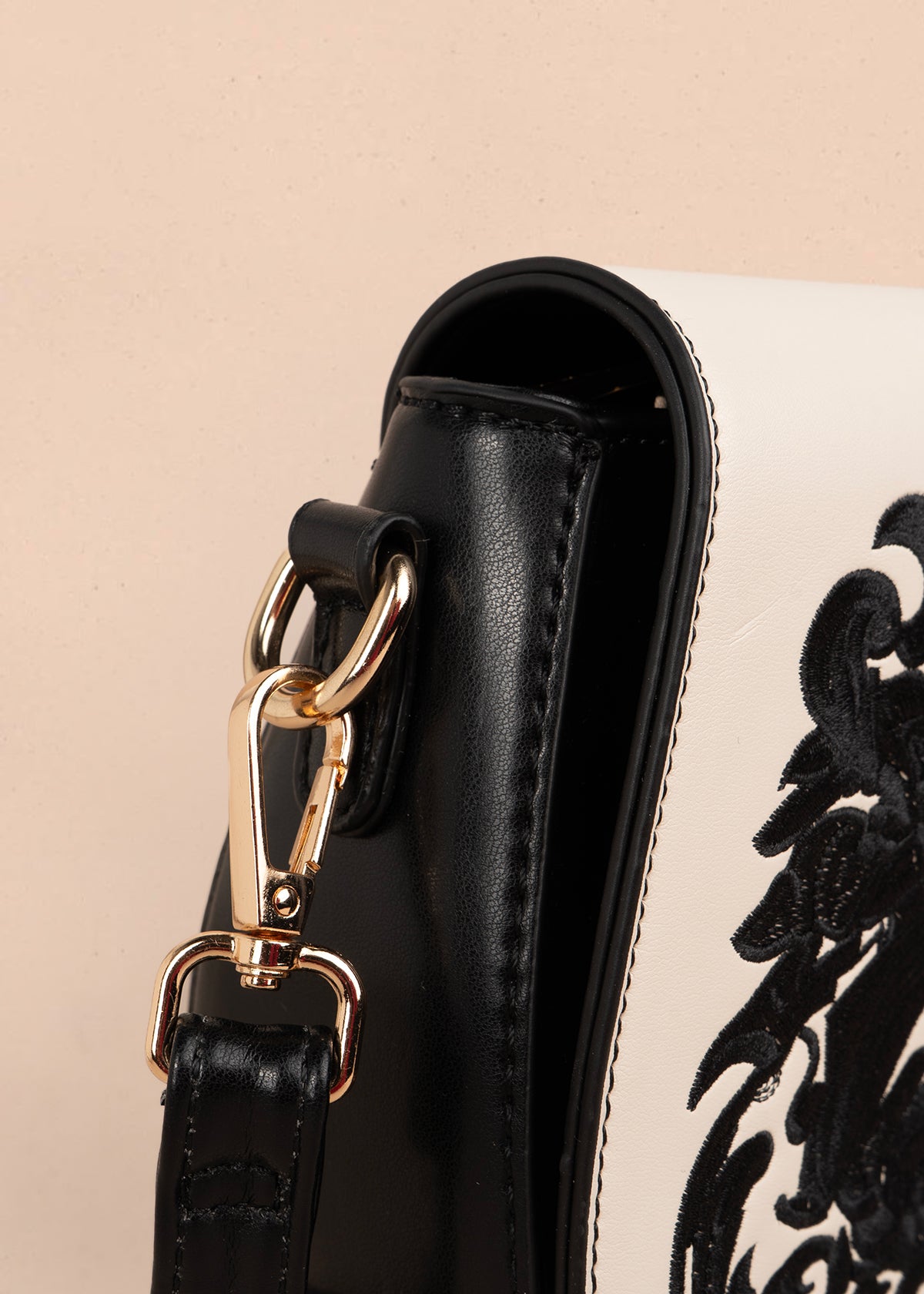 Bolso manos libres color negro con bordado y detalles dorados 106180