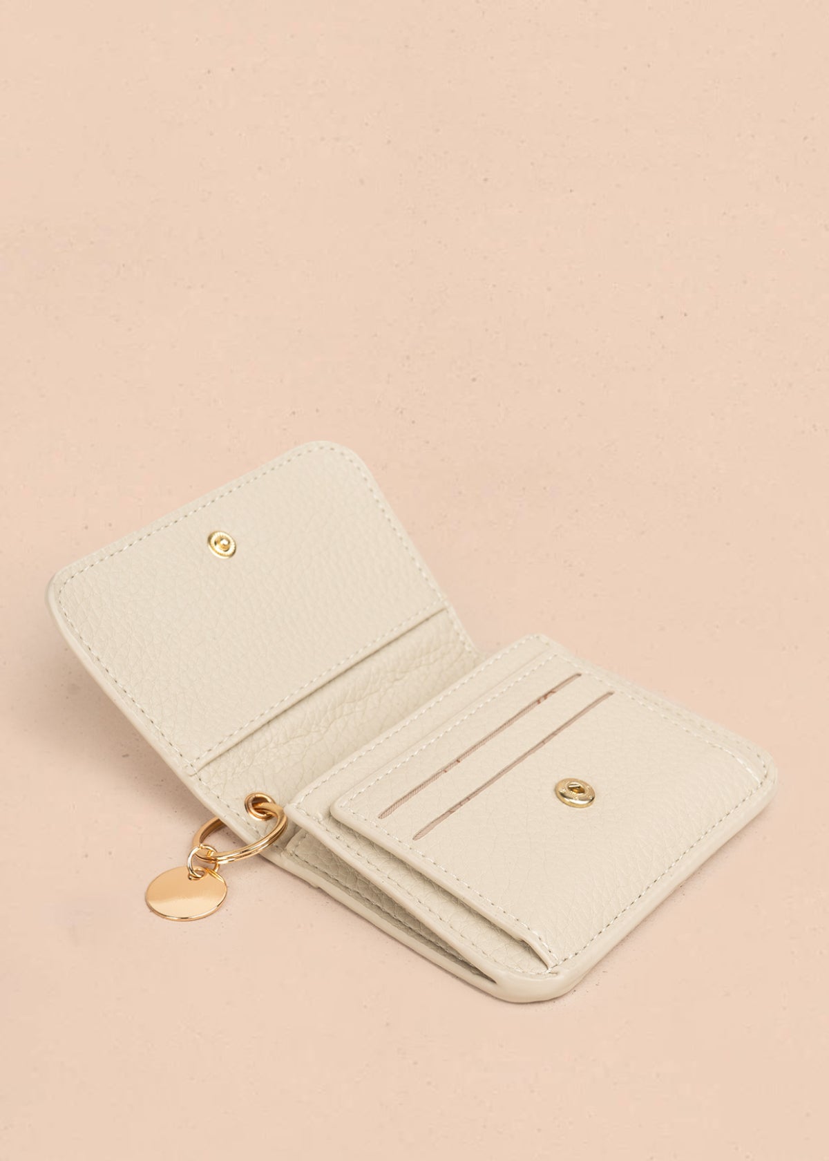Billetera pequeña color beige con cierre de solapa y aplique dorado 106185