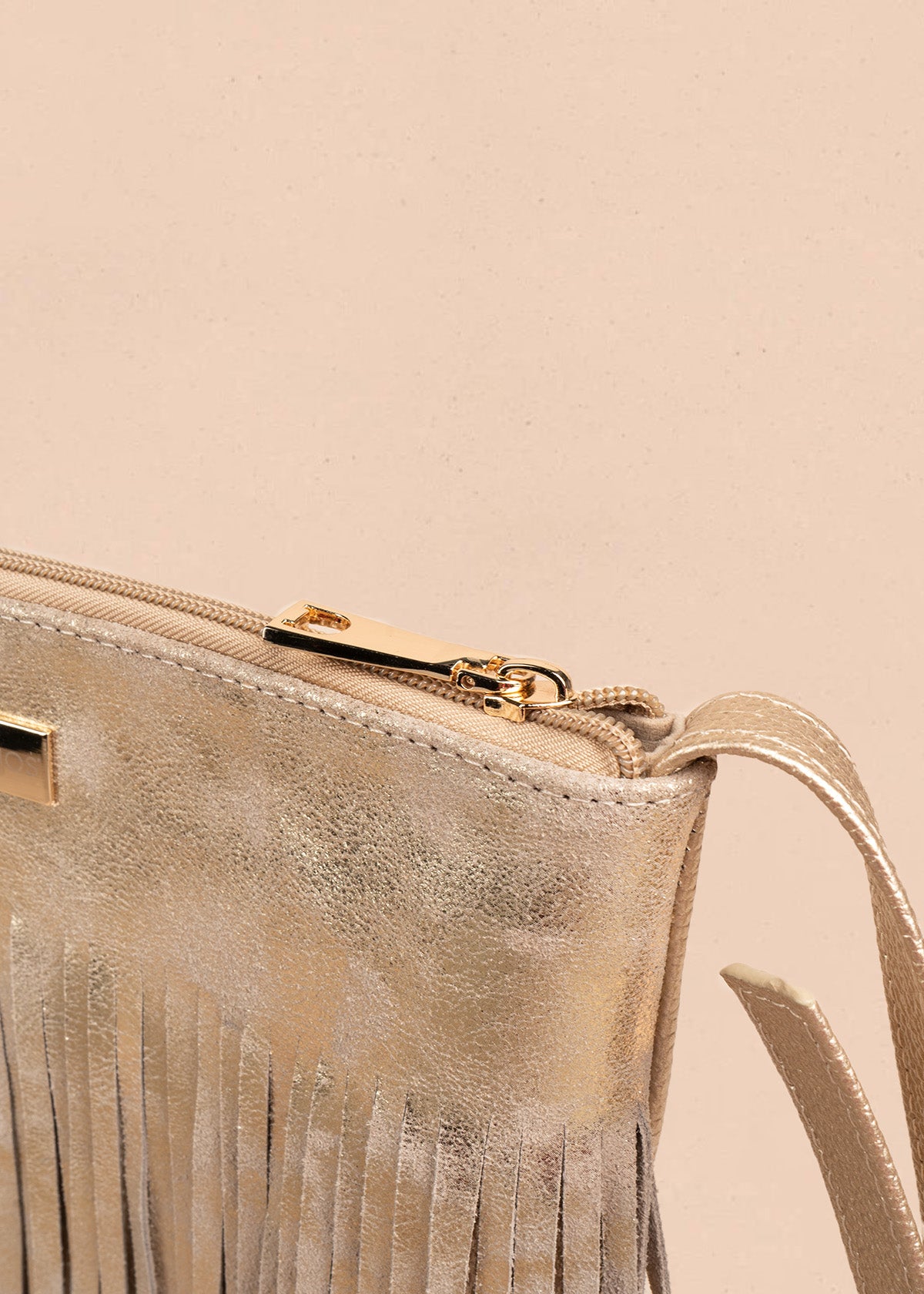 Bolso manos libres de cuero color arena con flecos 106633