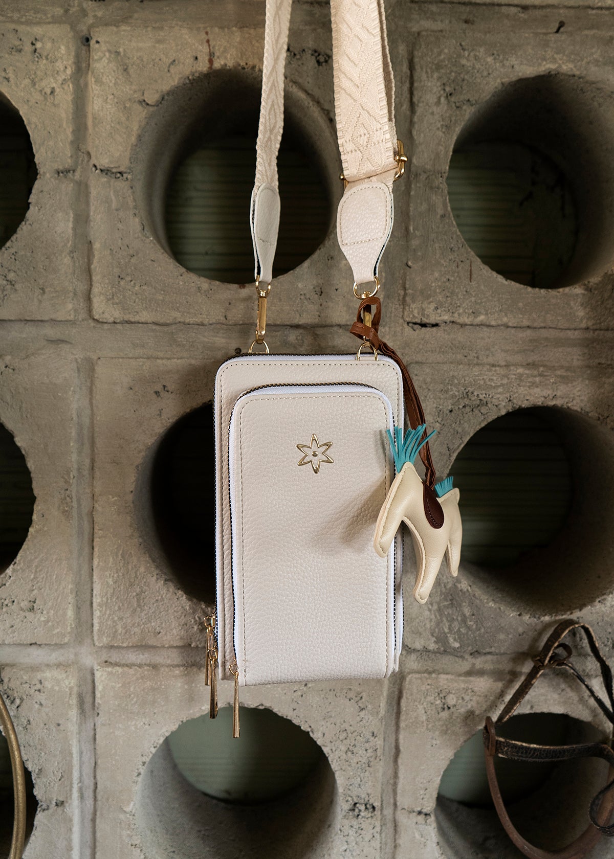 Porta celular color crema con llavero de caballo y detalles marrón 106186