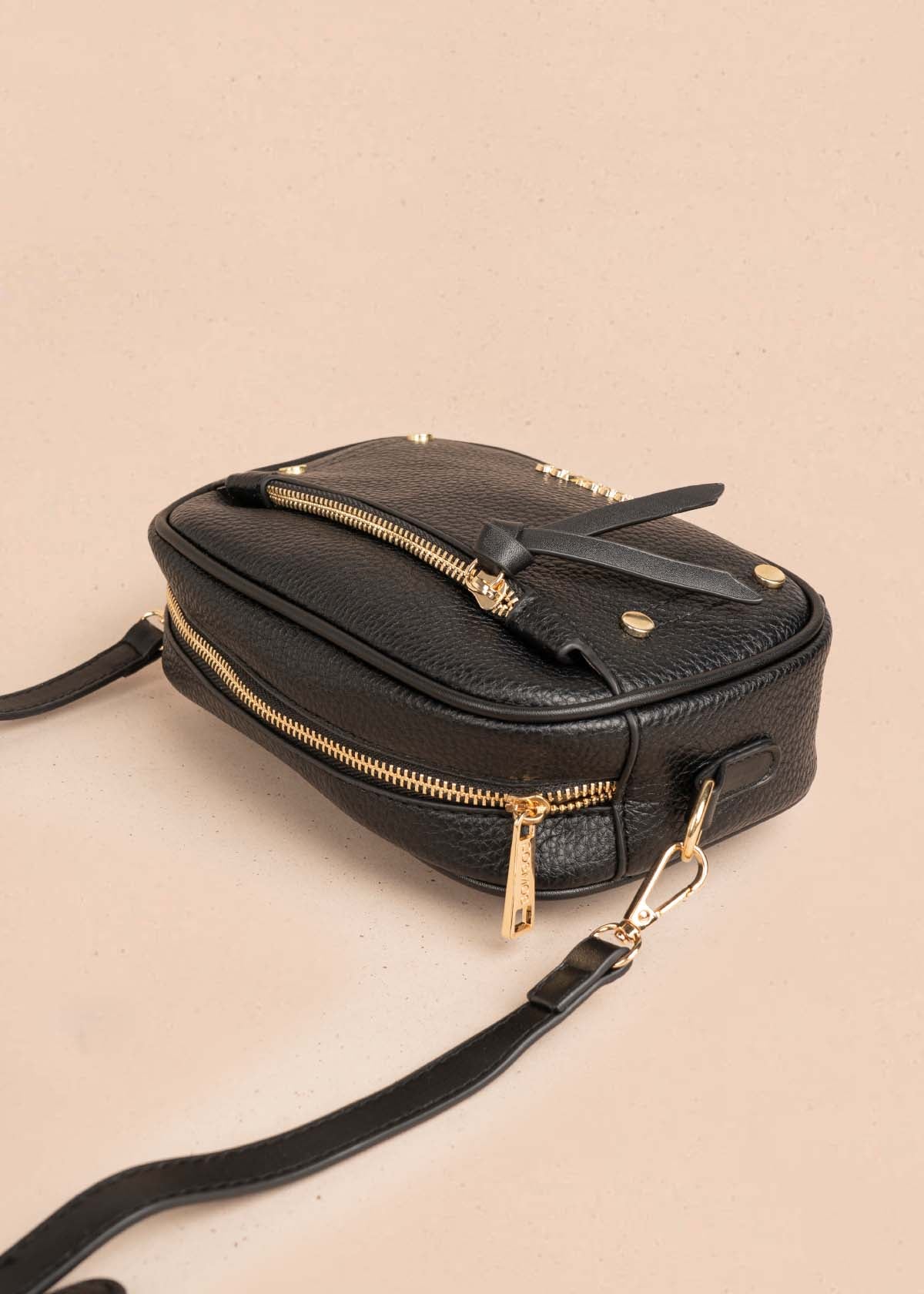 Bolso manos libres color negro con ribete y tachuelas doradas 106332