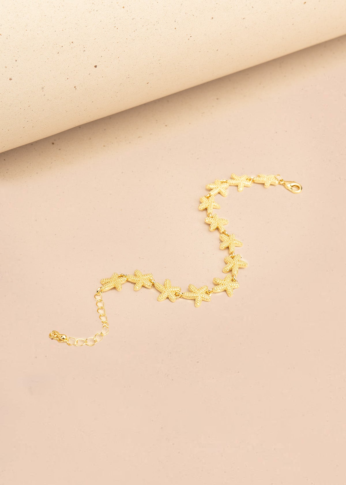 Pulsera color dorado con dijes de estrellas de mar 106397