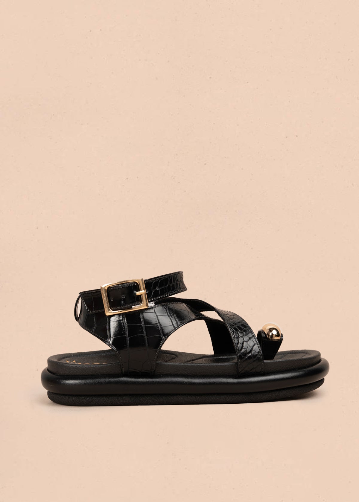 Sandalia plana color negro con correas cruzadas y detalle metálico dorado 106957